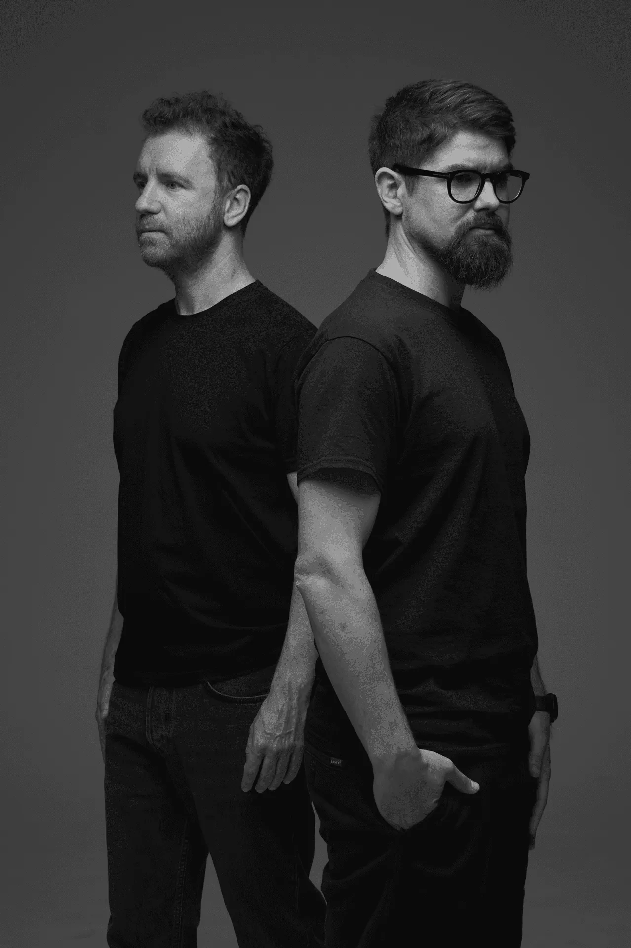 Black-and-white portrait of Sebastian Gratzer and Daniel Terler, back to back against a grey background, both in black T-shirts.