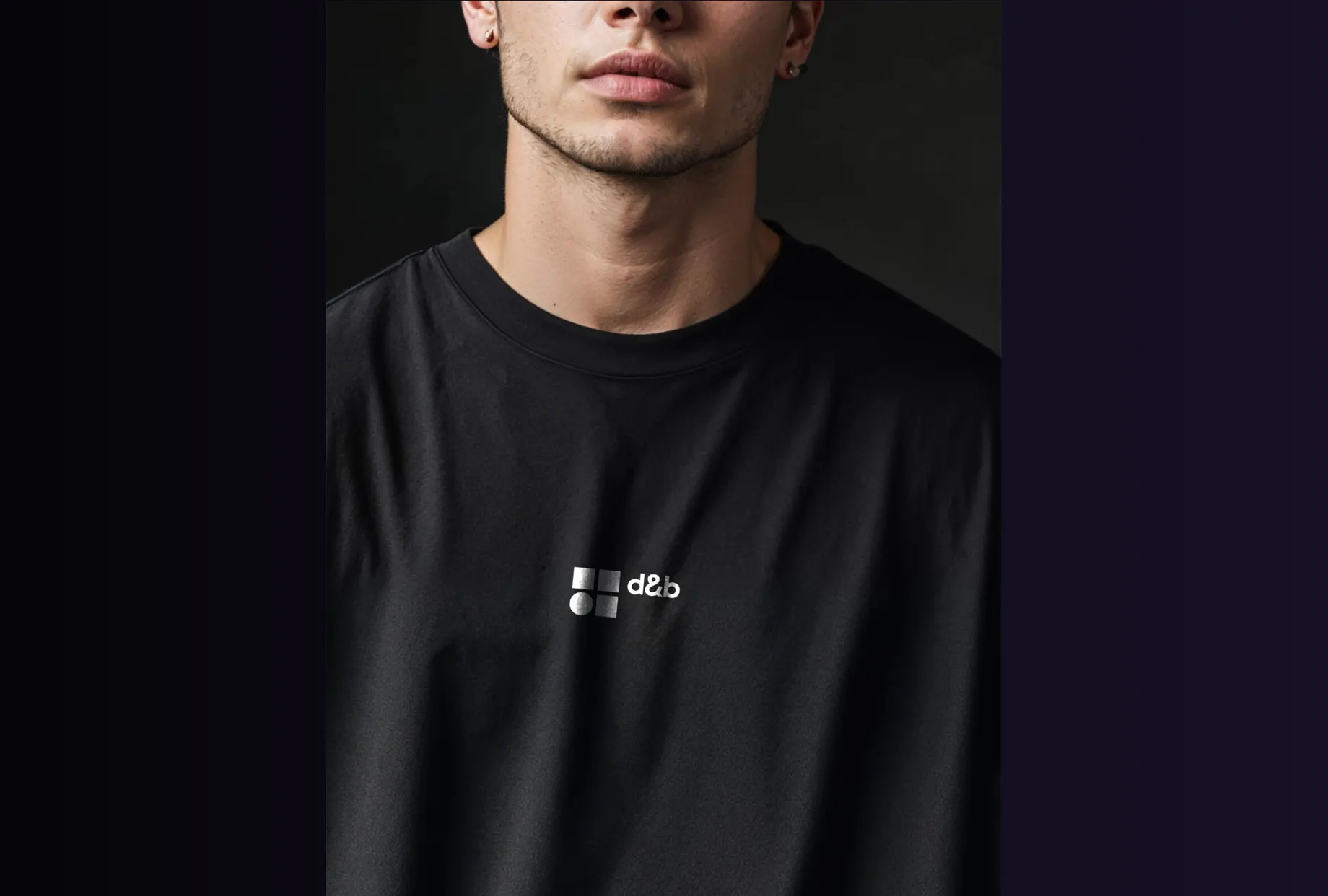 Schwarzes T-Shirt mit kleinem d&b-Logo auf der Brust, getragen von einer Person.