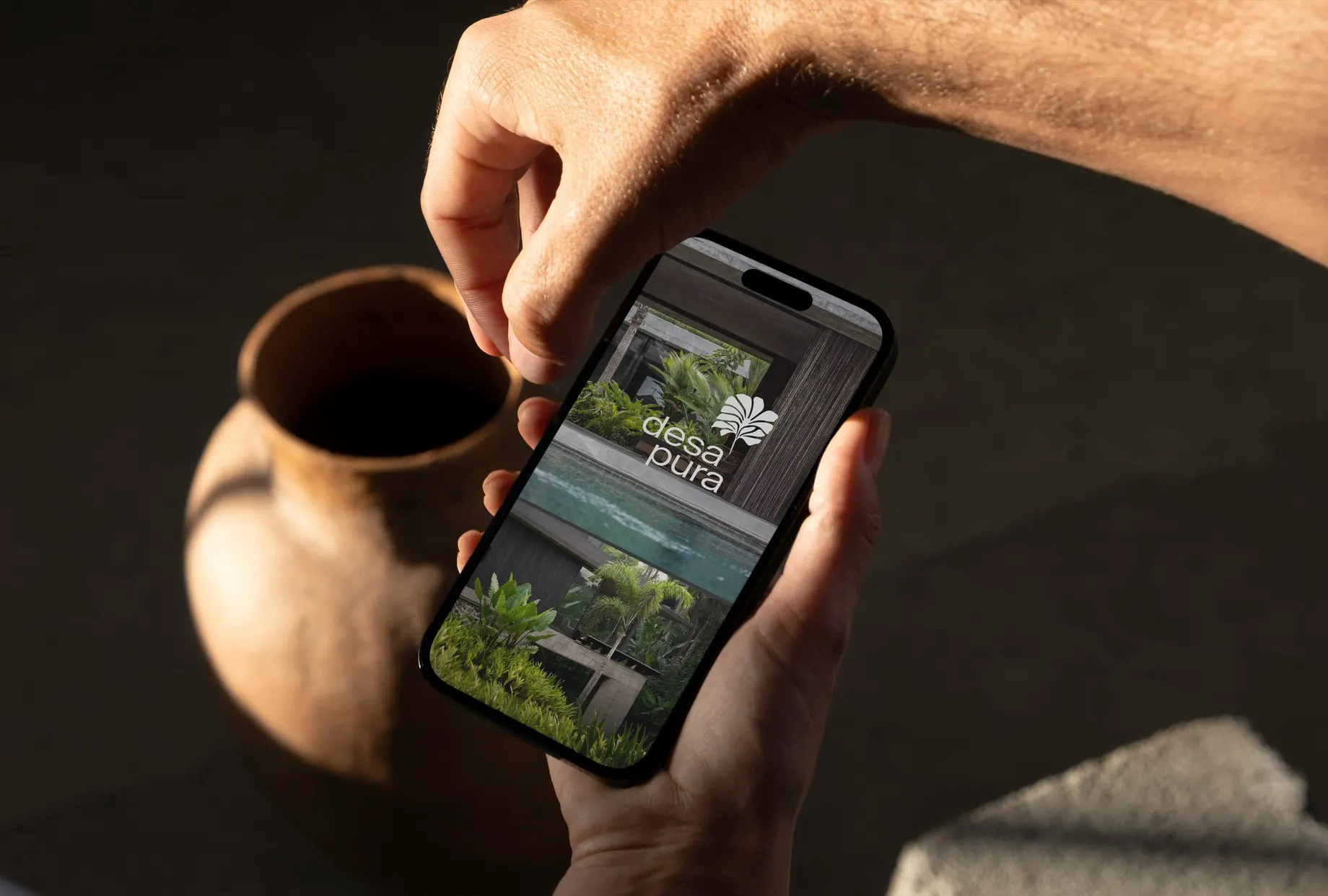 Logo des Desa Pura Wohnprojekts auf einem Smartphone, das Natur, Gemeinschaft und modernes Wohnen symbolisiert.
