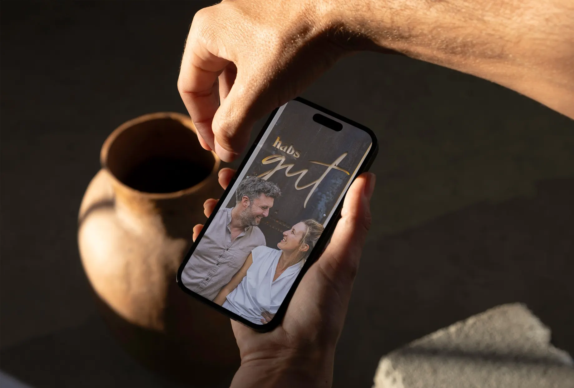 Hand hält ein Smartphone mit dem habs*gut-Auftritt auf dem Bildschirm.