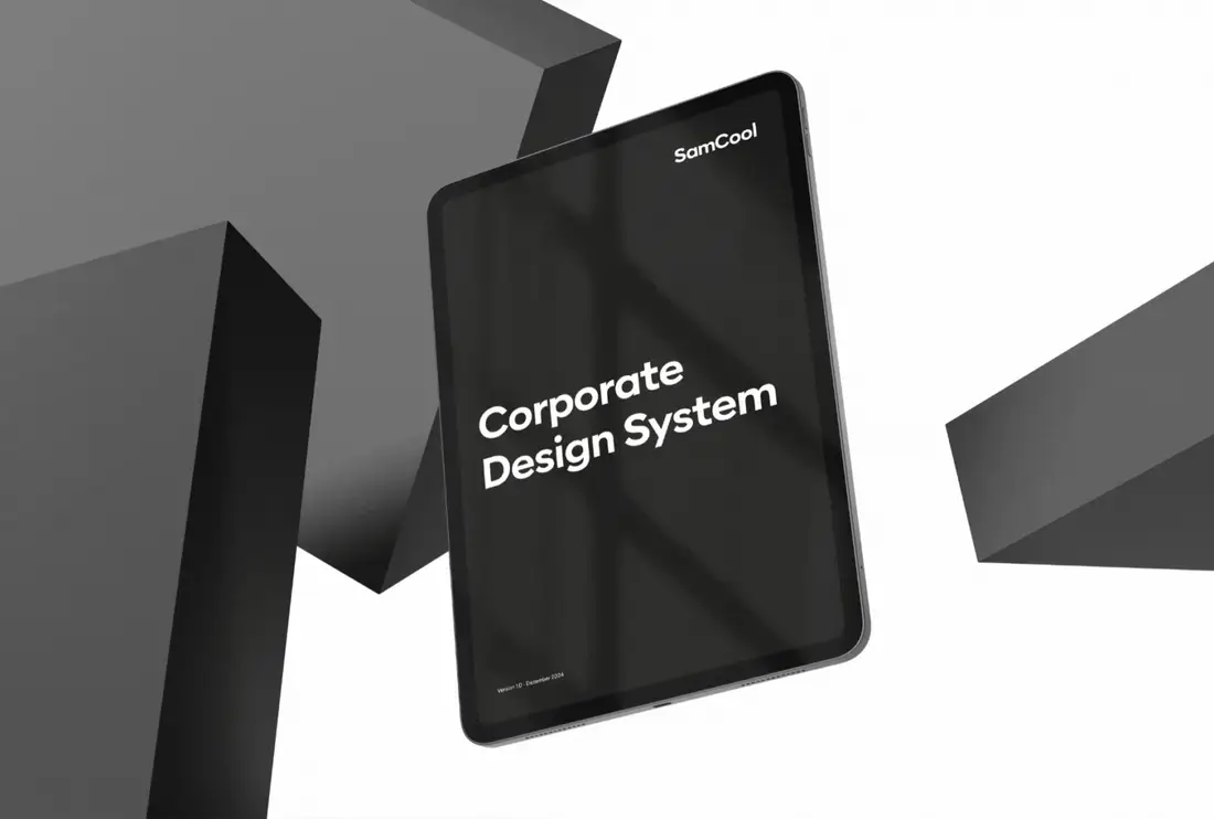 Tablet zwischen dunkelgrauen Quadern, auf dem Bildschirm der Titel „Corporate Design System“ mit dem SamCool-Logo.